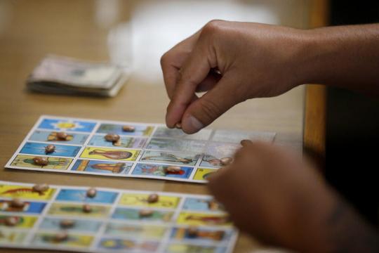 Hand holding a bean playing loteria