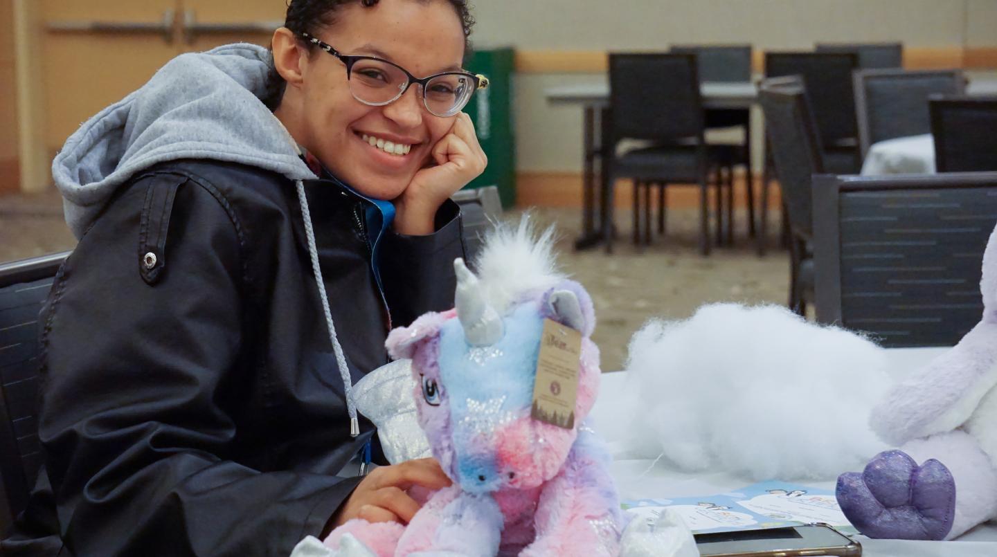 student sitting at a table next to stuffed animal