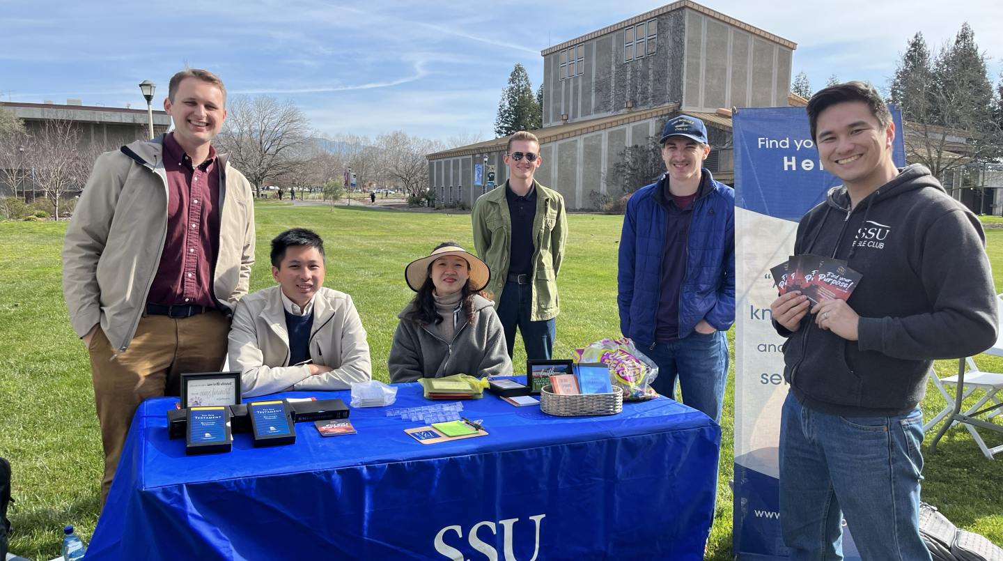 a group of students in front of a blue table that says SSU Bible Club