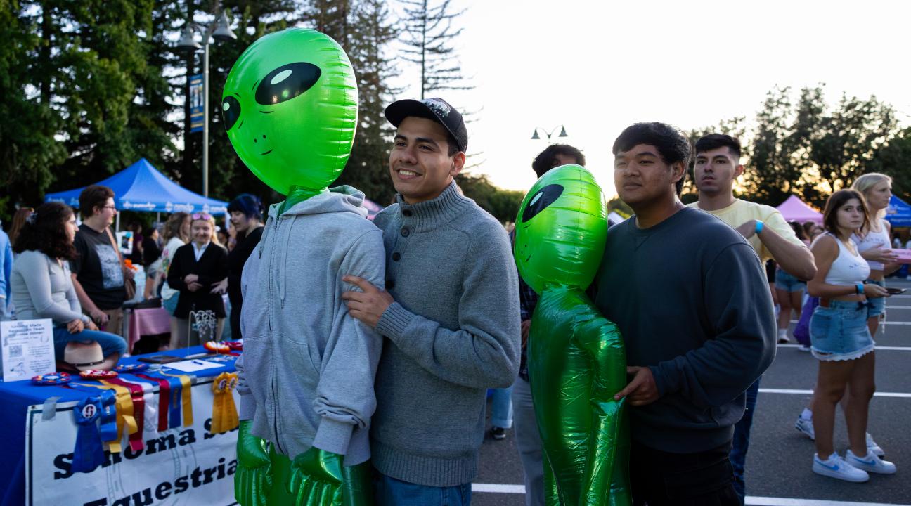 2 students carrying inflatable aliens