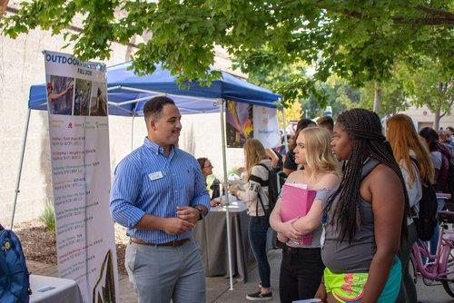 students speaking with a representative at a tabling event