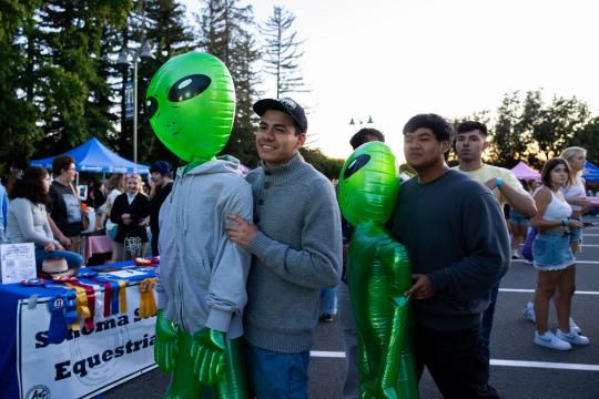 2 students carrying inflatable aliens