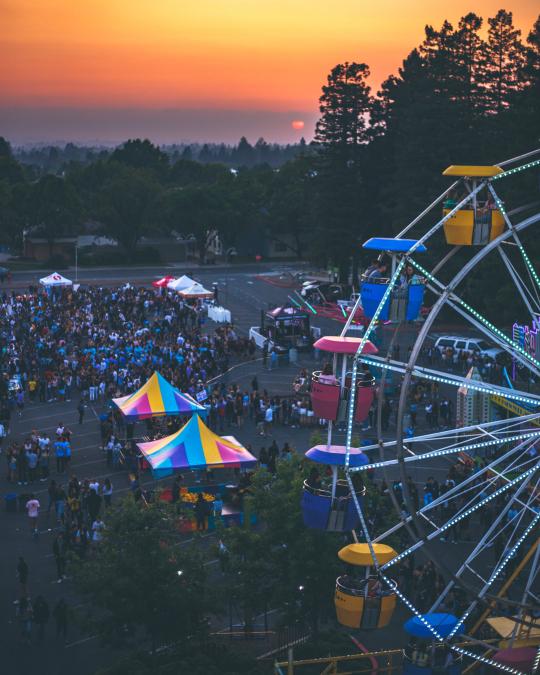 Ferris wheel and carnival tents with people 