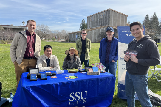 a group of students in front of a blue table that says SSU Bible Club