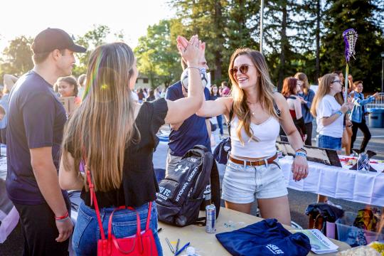 Two girls greeting each other at a tabling event 