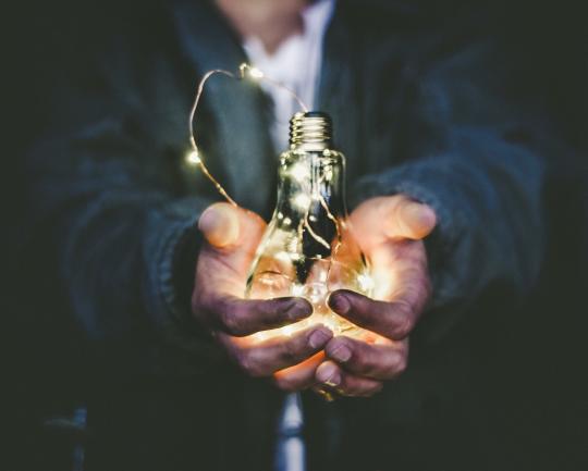 Person holding lit up lightbulb