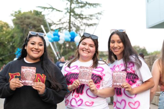 three students holding up a sign for their sorority